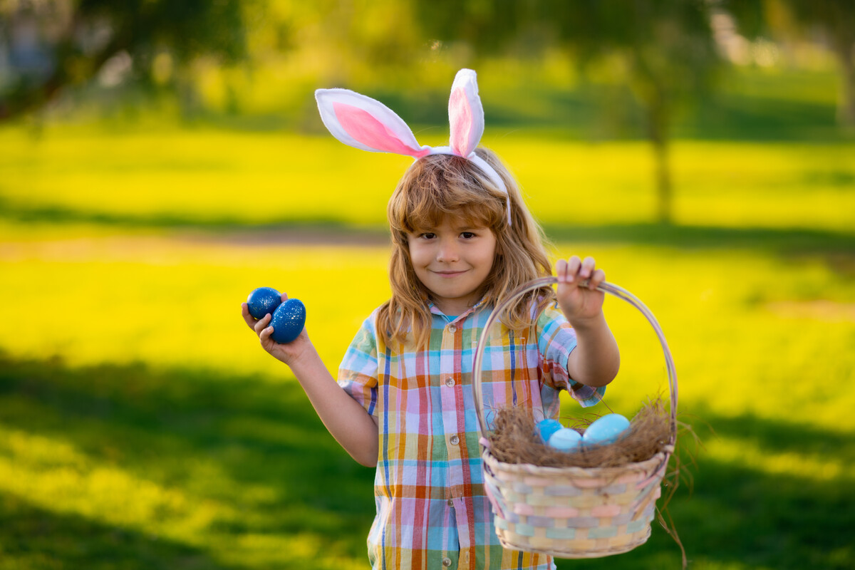 A boy in bunny ears hunting easter eggs outdoors during our Jackson easter egg hunt in 2023.